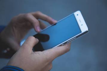 close up of someone's hands holding cell phone to book junk removal services