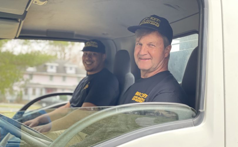 Two employees from Rocket Junk Removal smiling sitting in truck