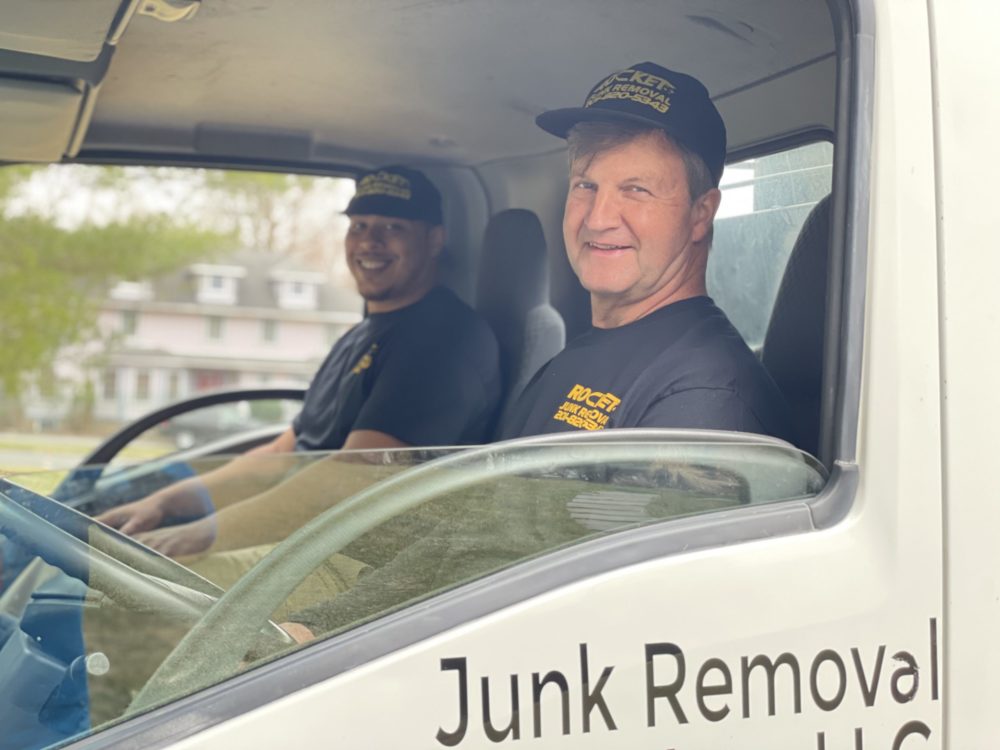 rocket junk removal employees in truck smiling