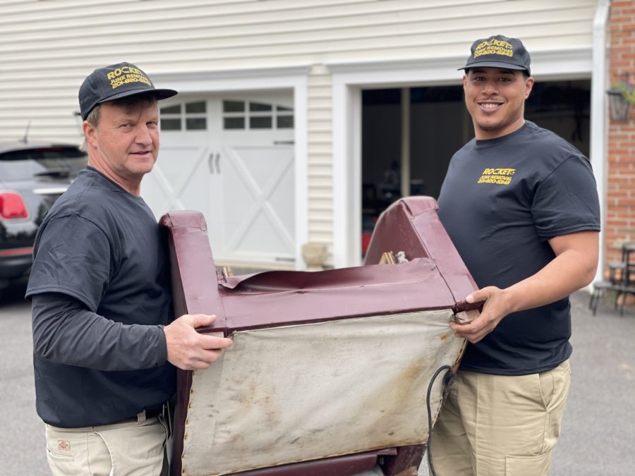 Rocket junk removal experts carrying old couch to truck