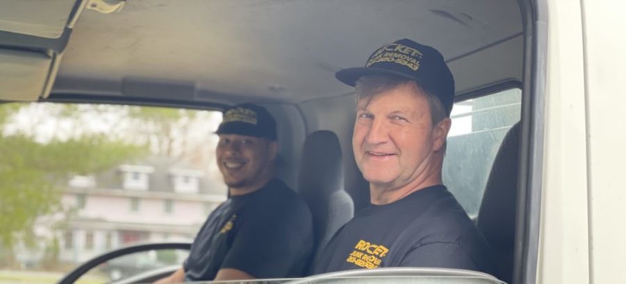 two people sitting and smiling in a junk removal truck with rocket junk removal