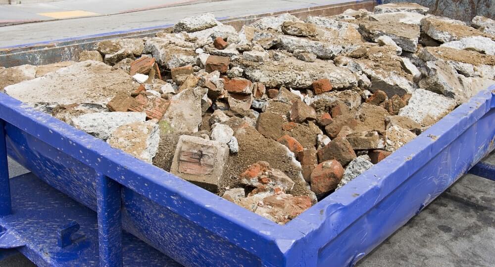 Broken up concrete in a blue bin for construction debris removal